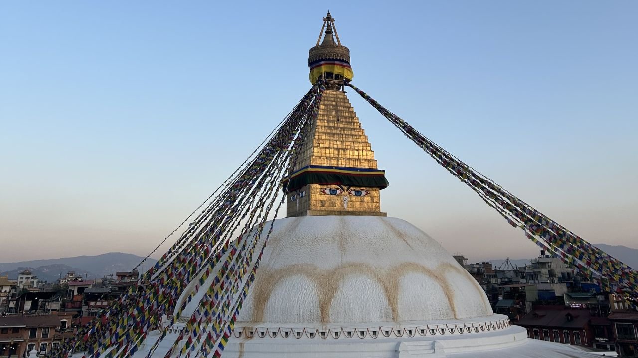 Boudhanath Stupa glowing at sunset with prayer flags